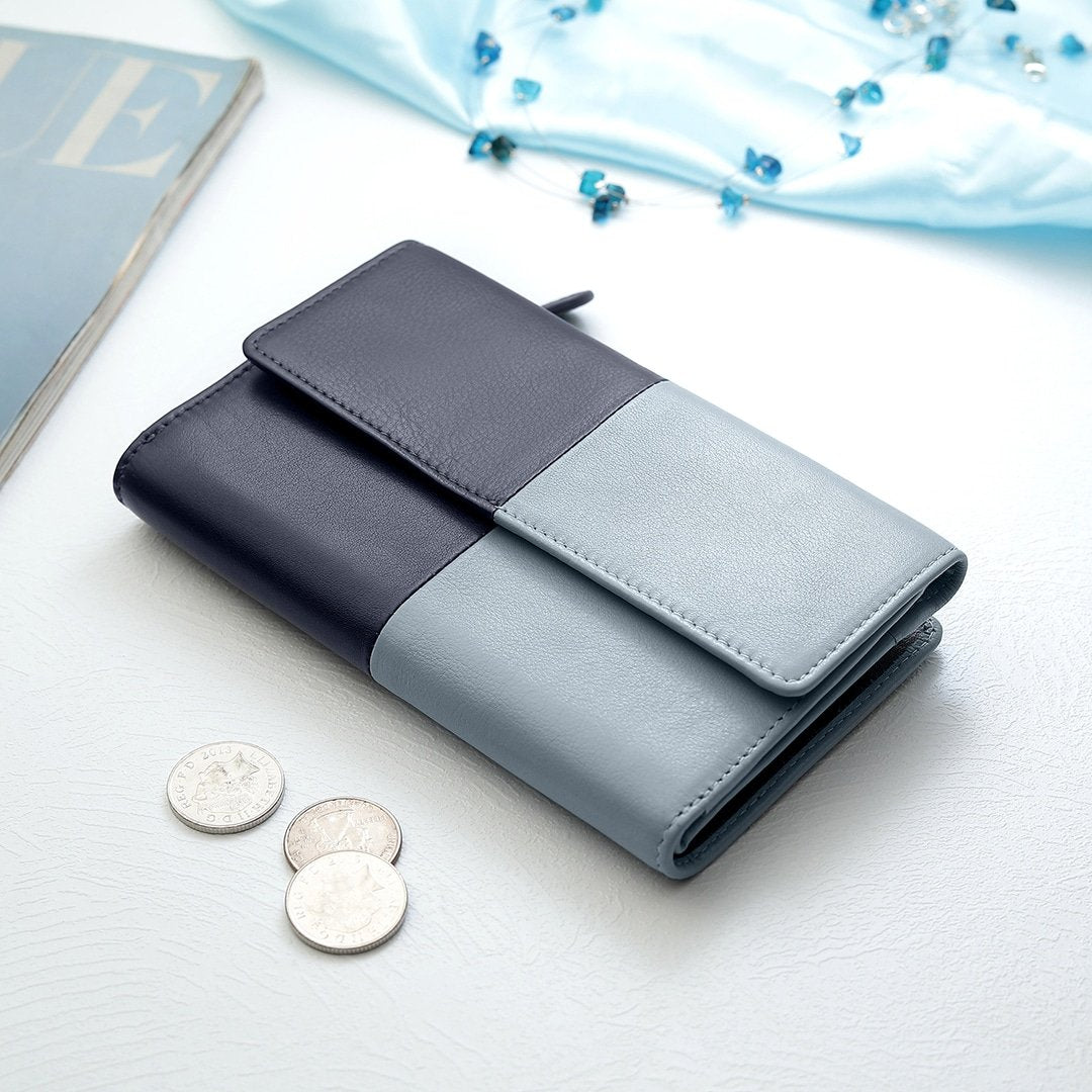 Clara Flapover Purse in navy and blue, closed and placed on a table, highlighting its modern and stylish appearance.