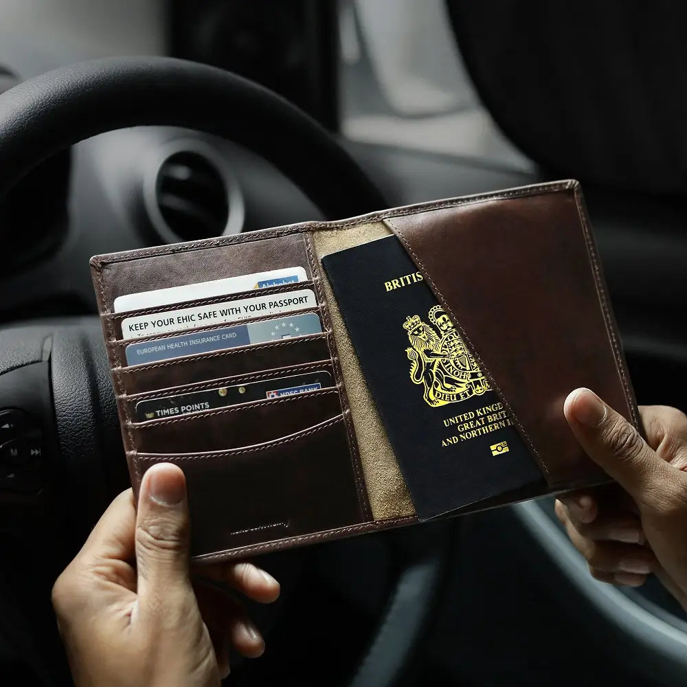 Person holding a brown leather wallet with a British passport inside, car interior background