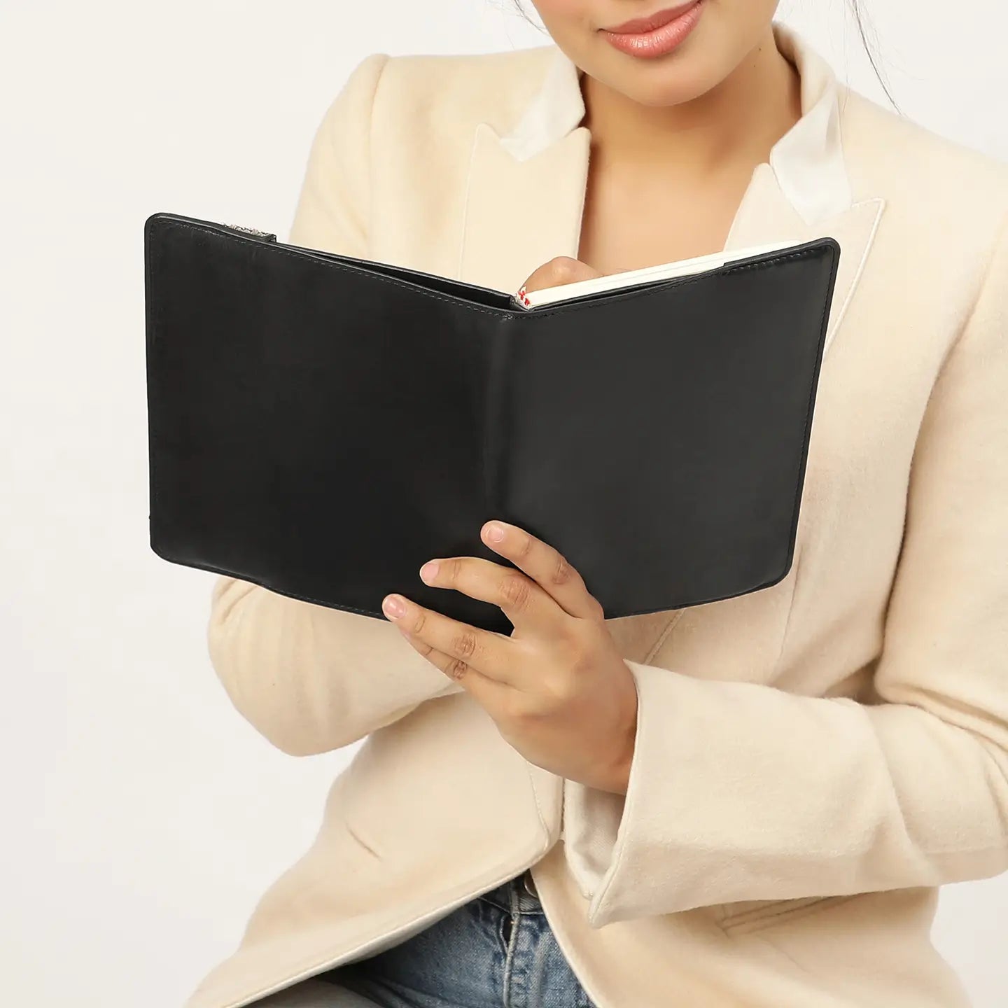Person holding a black leather notebook against a plain background