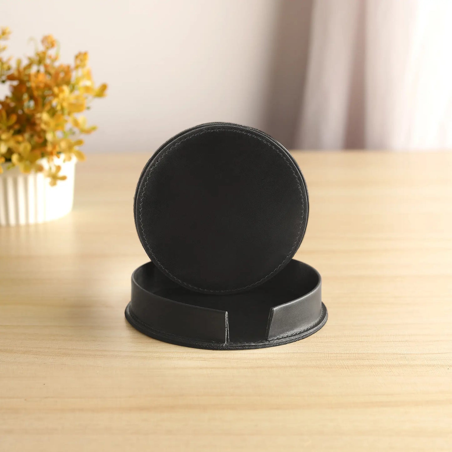 Black coaster set on a wooden surface with a blurred background