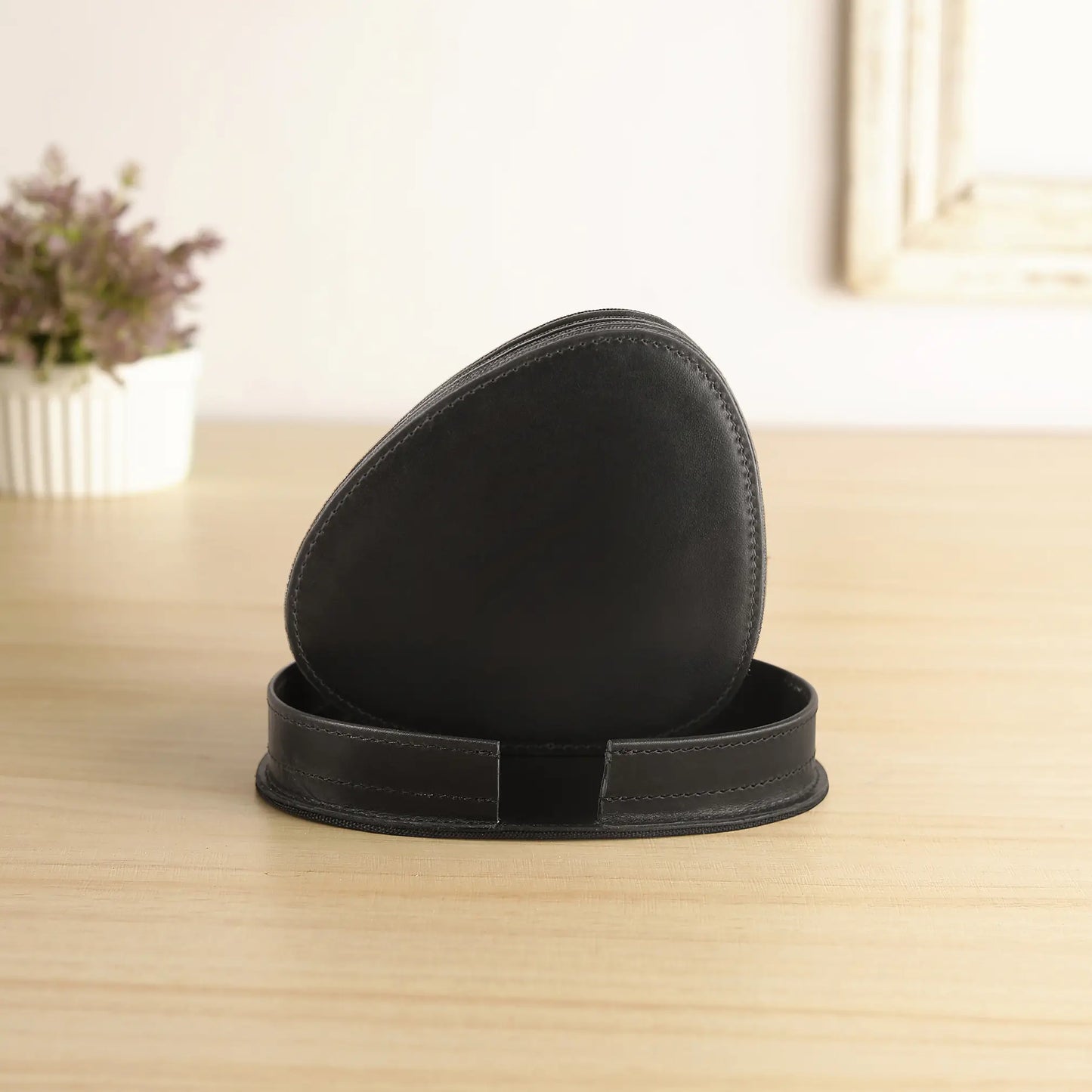 Black leather coaster set on a wooden surface with a blurred background
