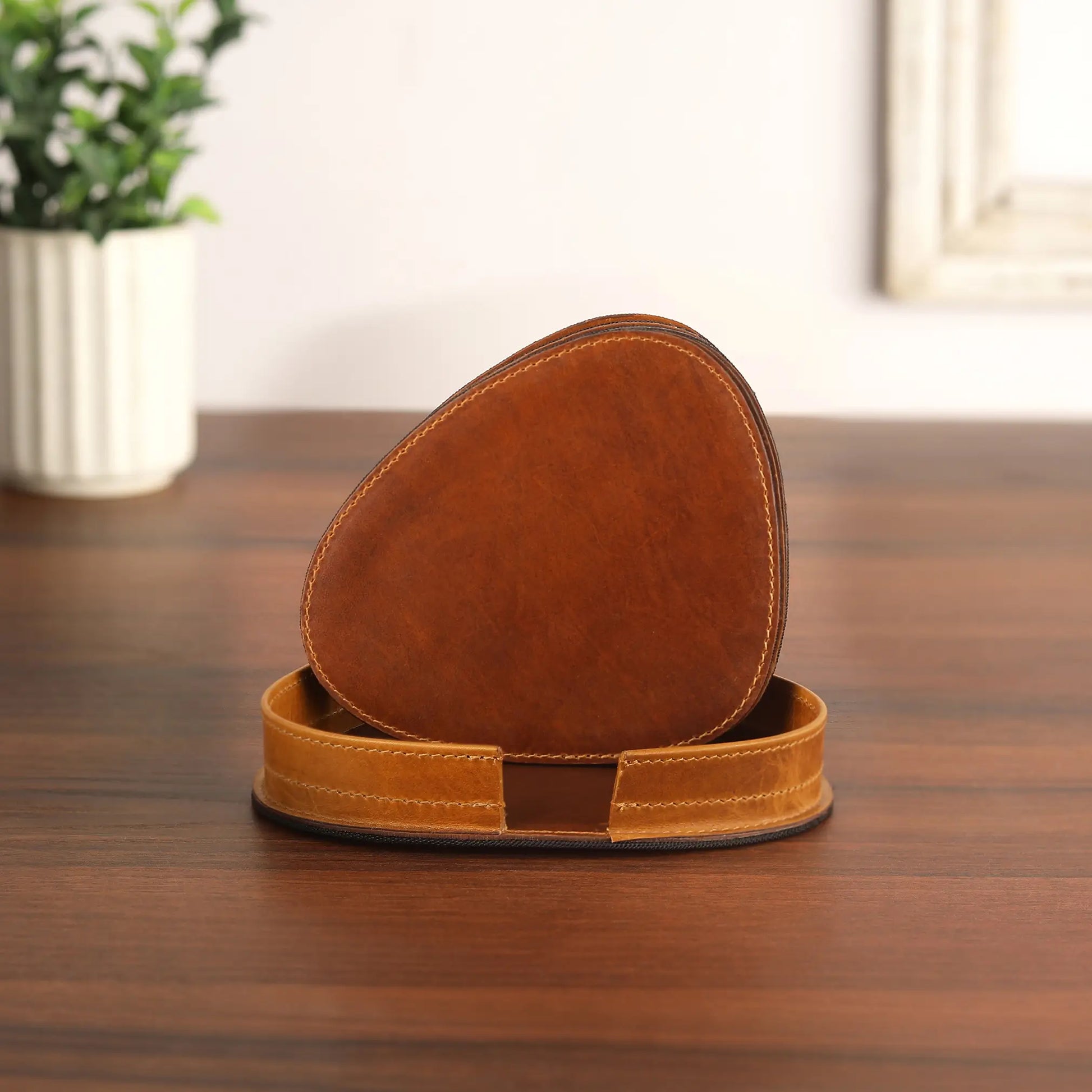 Tan leather coaster with a matching leather patch on a wooden surface.