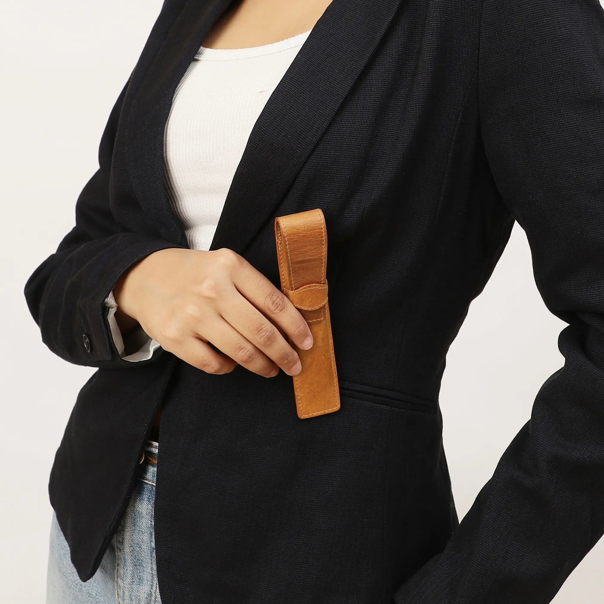 Person holding a tan leather pen holder against a neutral background